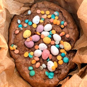 Slow cooker brownies in pot, covered in chocolate mini eggs.