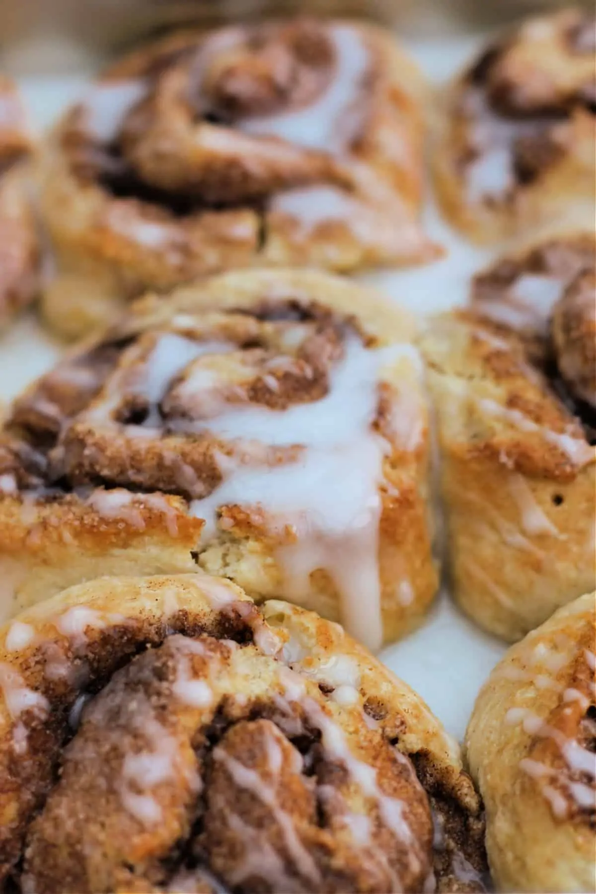 Close up of cinnamon rolls with icing drizzles.