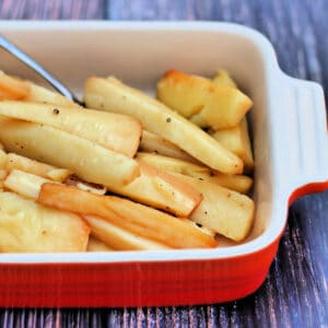 Slow cooker roast parsnips in red serving dish.