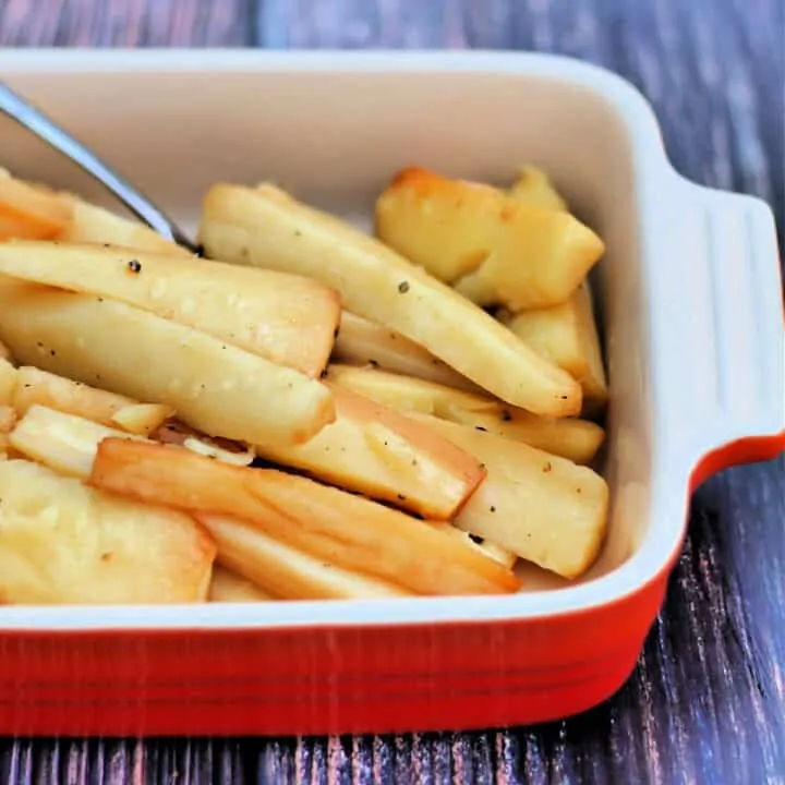 Slow cooker roast parsnips in red serving dish.
