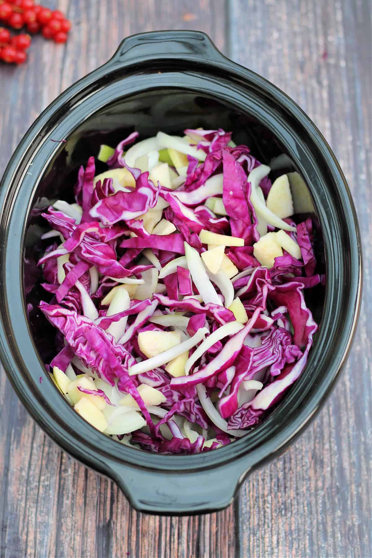 Slow cooker full of shredded cabbage, onion and apple.