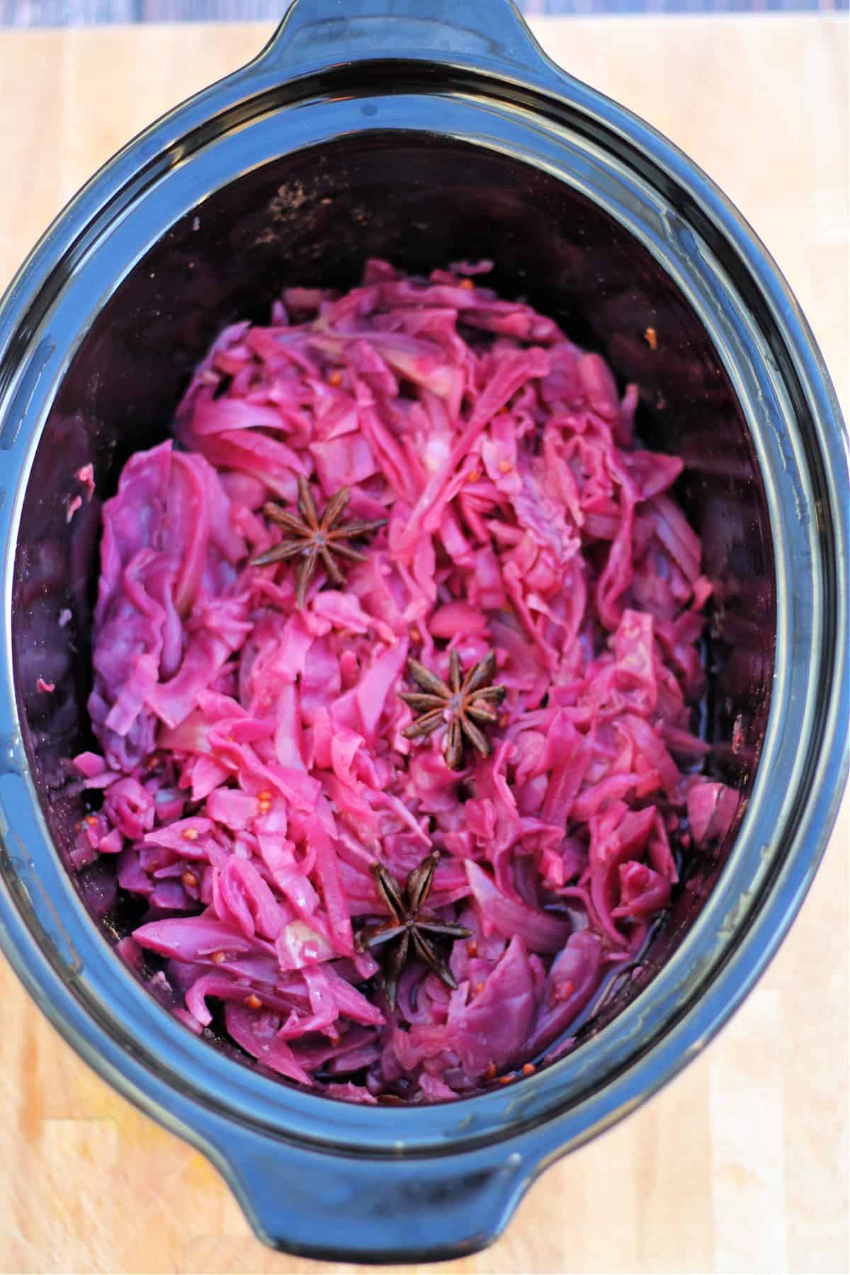 Cooked braised red cabbage with apple in slow cooker pot.