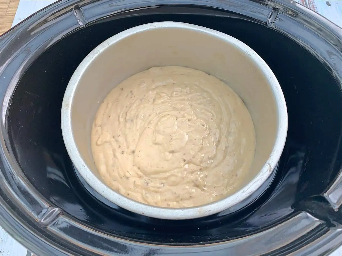 Cake tin with cake mixture in a slow cooker.