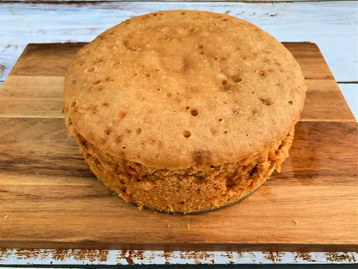 Slow cooker cake from tin cooling on a board.