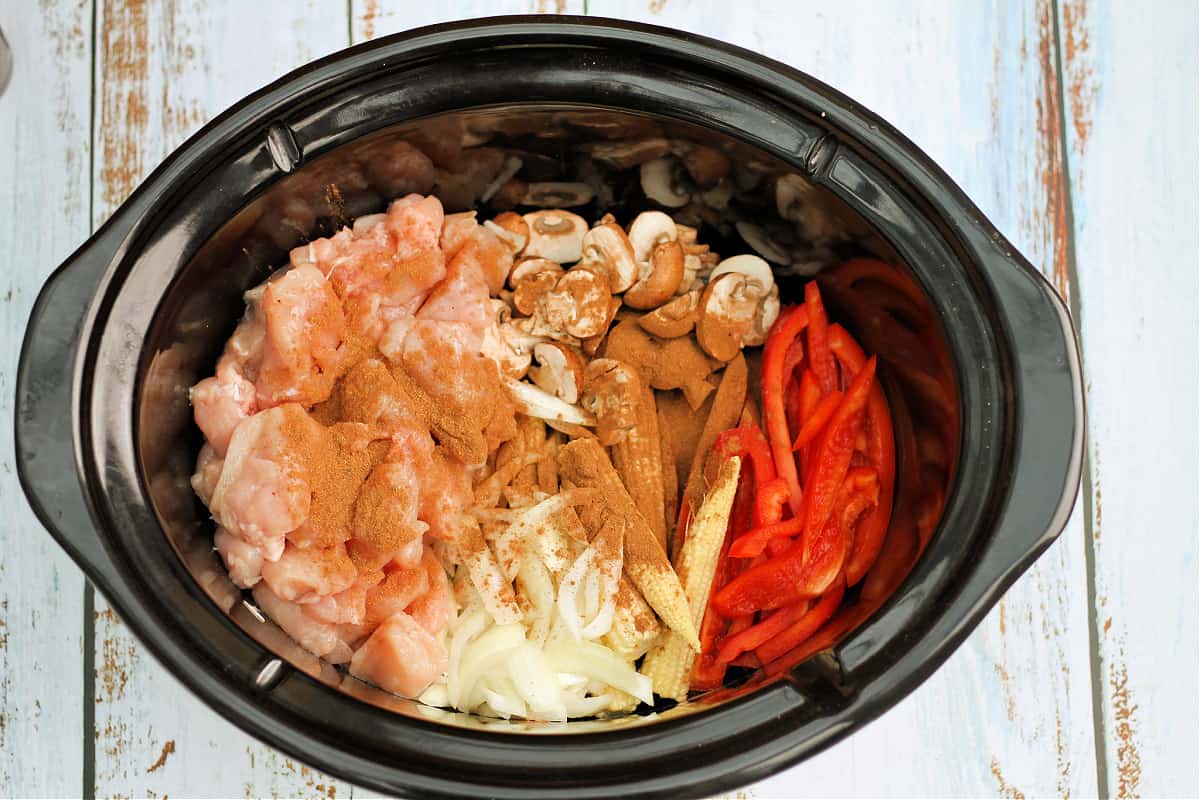 Diced chicken, onion, baby corn, red peppers and mushrooms in slow cooker pot, with Chinese five spice sprinkled over the top.