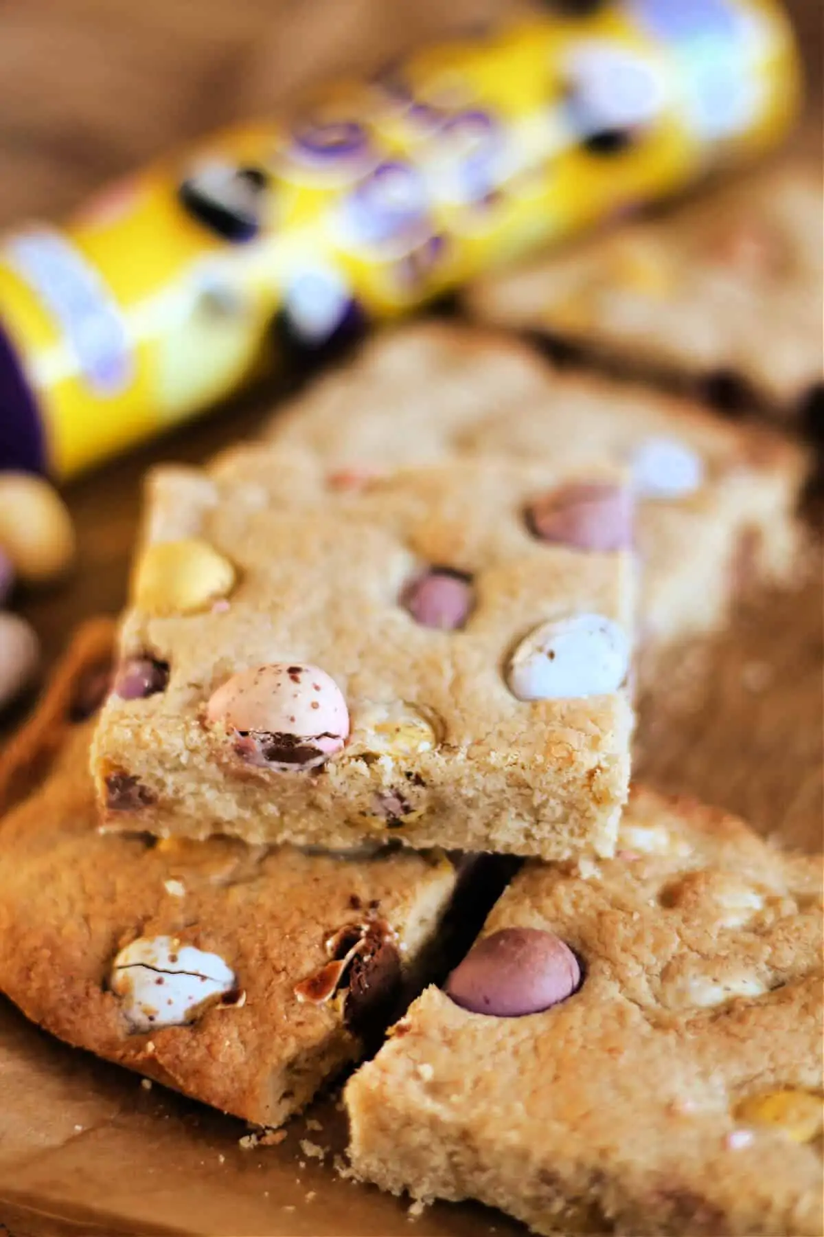 Stack of cookie bars with tube of mini eggs in background.