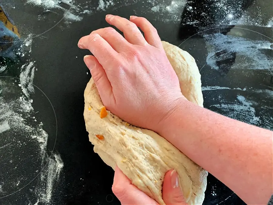 Kneading technique shown with the heel of the hand pushing the dough away.