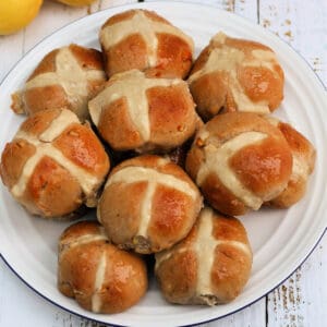 Close up of hot cross buns on a white plate.