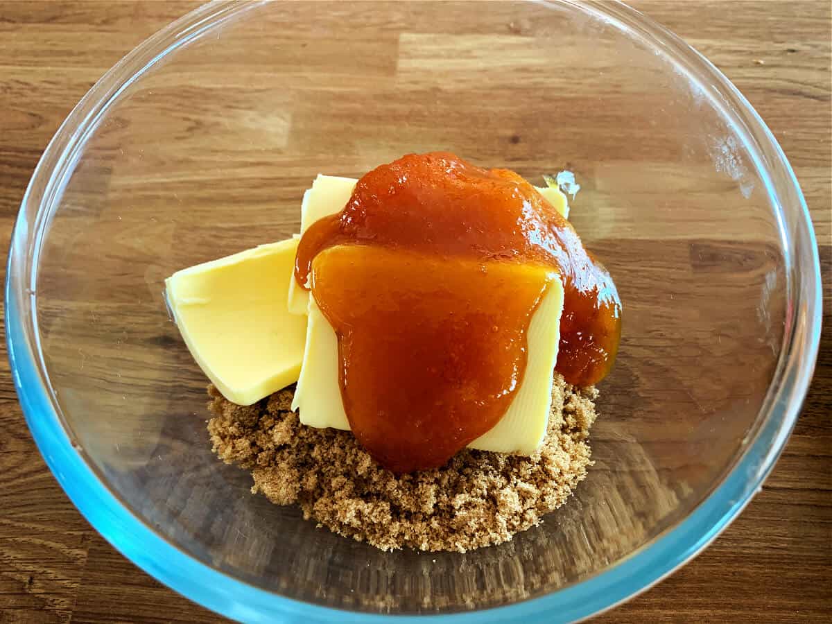 Glass bowl containing brown sugar, butter and golden syrup.