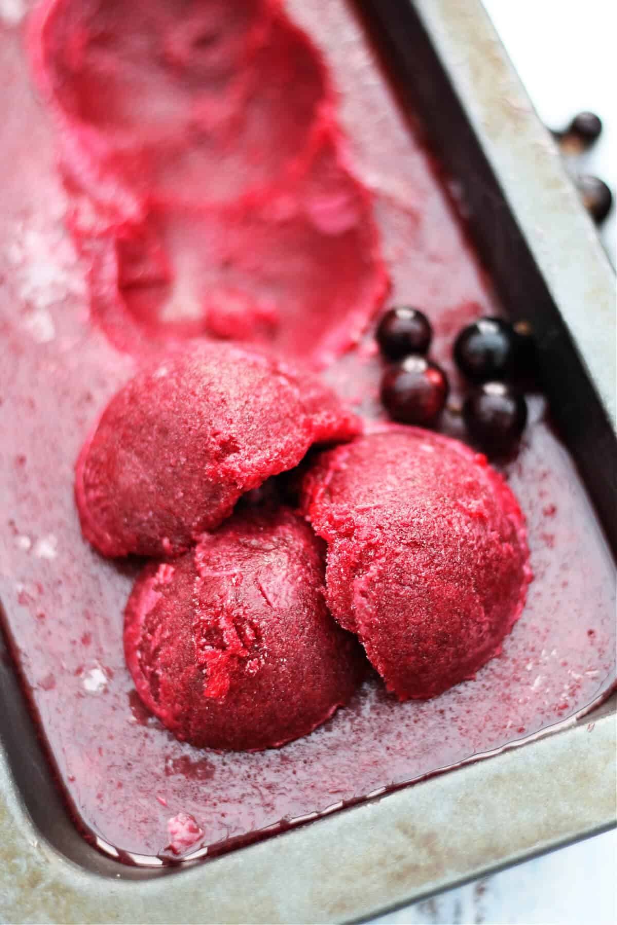 Three scoops of sorbet on top of a frozen tin of sorbet.