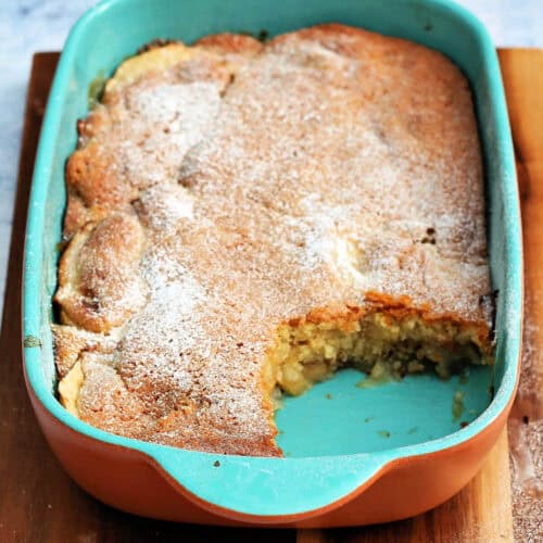 Baked apple sponge pudding in a teal serving dish,
