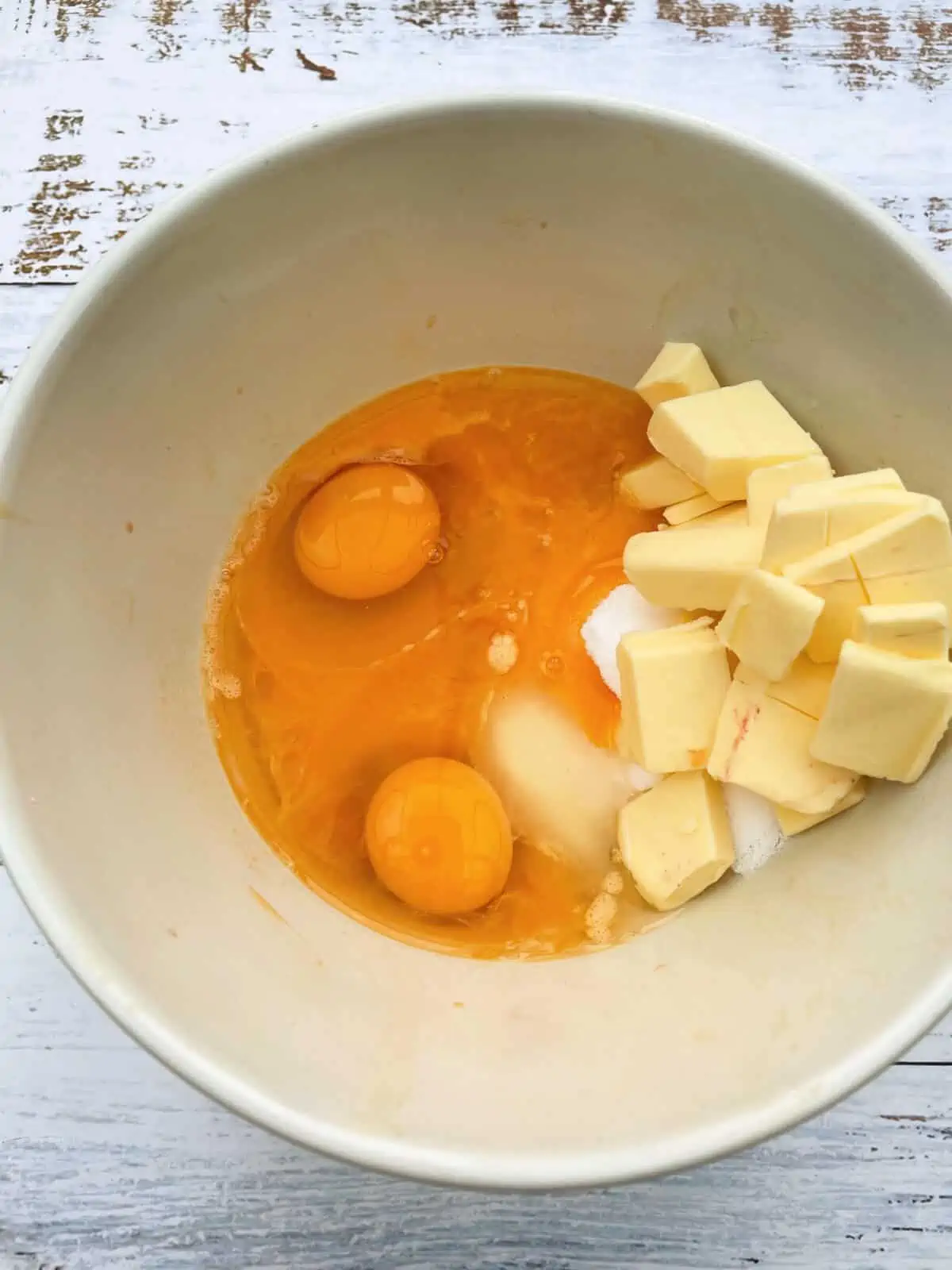 Bowl containing eggs, sugar, butter and passionfruit juice.