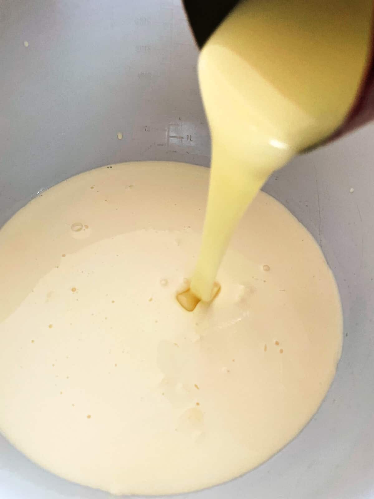 Pouring condensed milk into bowl of double cream.