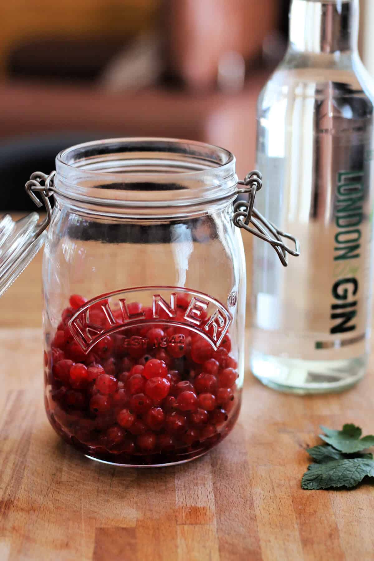 Redcurrants in a jar, gin bottle in background.
