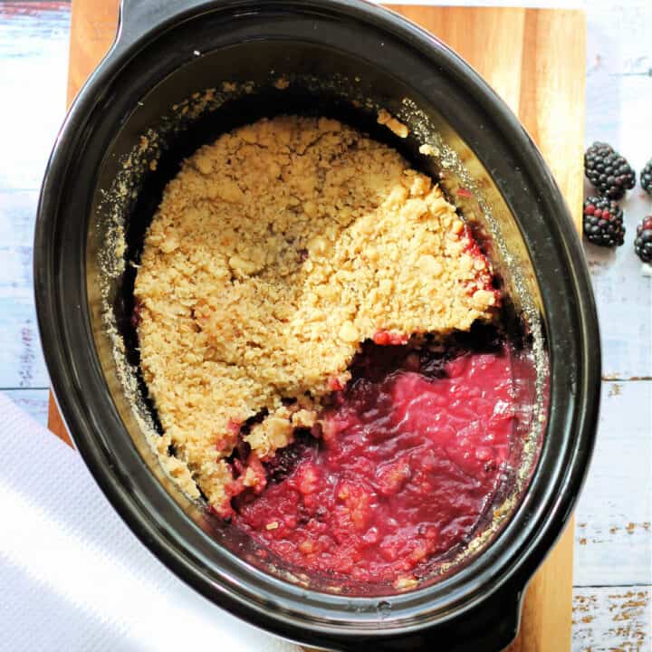 Blackberry crumble in a black slow cooker pot.