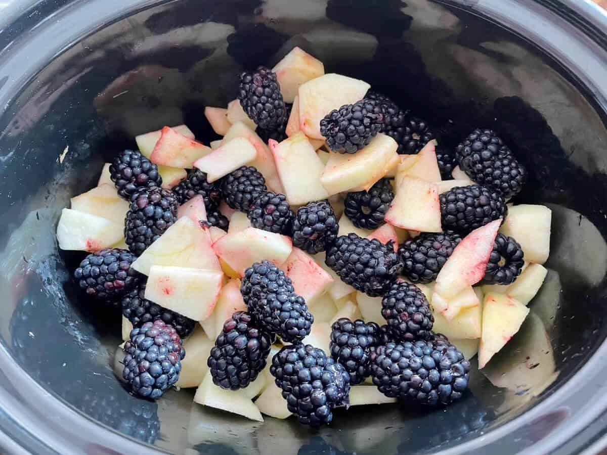 Blackberries and sliced apple in slow cooker pot.