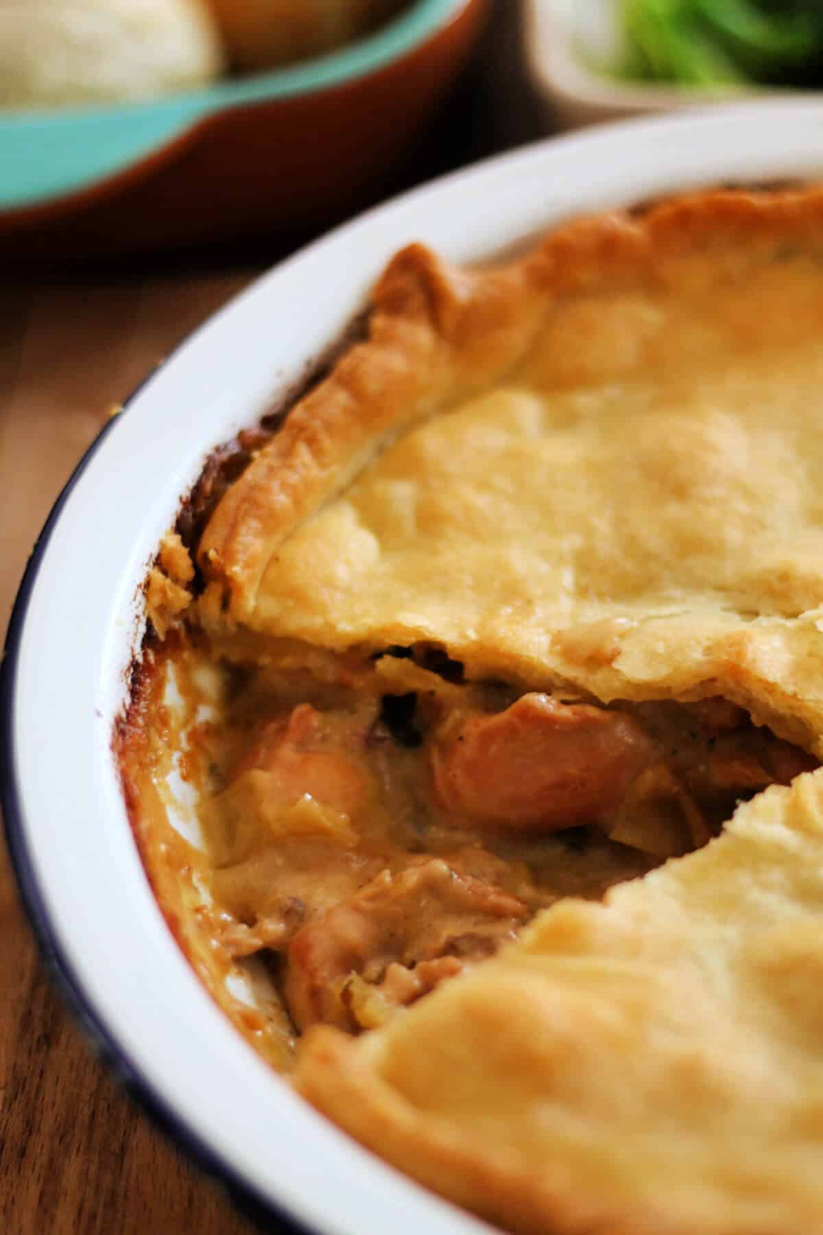 Chicken pie in a white dish, with a slice removed showing the filing.