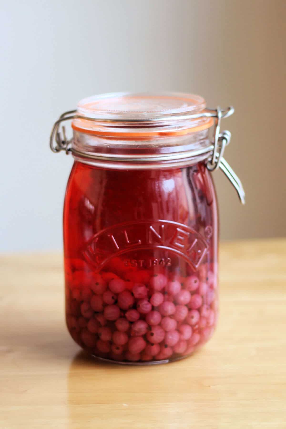 Red gin in a kilner jar on a table.