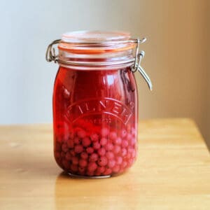 Redcurrant gin in jar, on table.