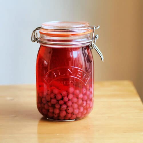 Redcurrant gin in jar, on table.