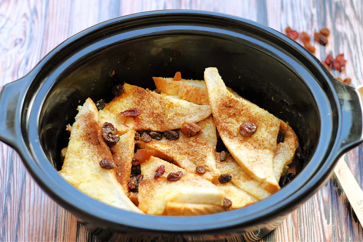 Side view of baked bread and butter pudding in slow cooker pot.