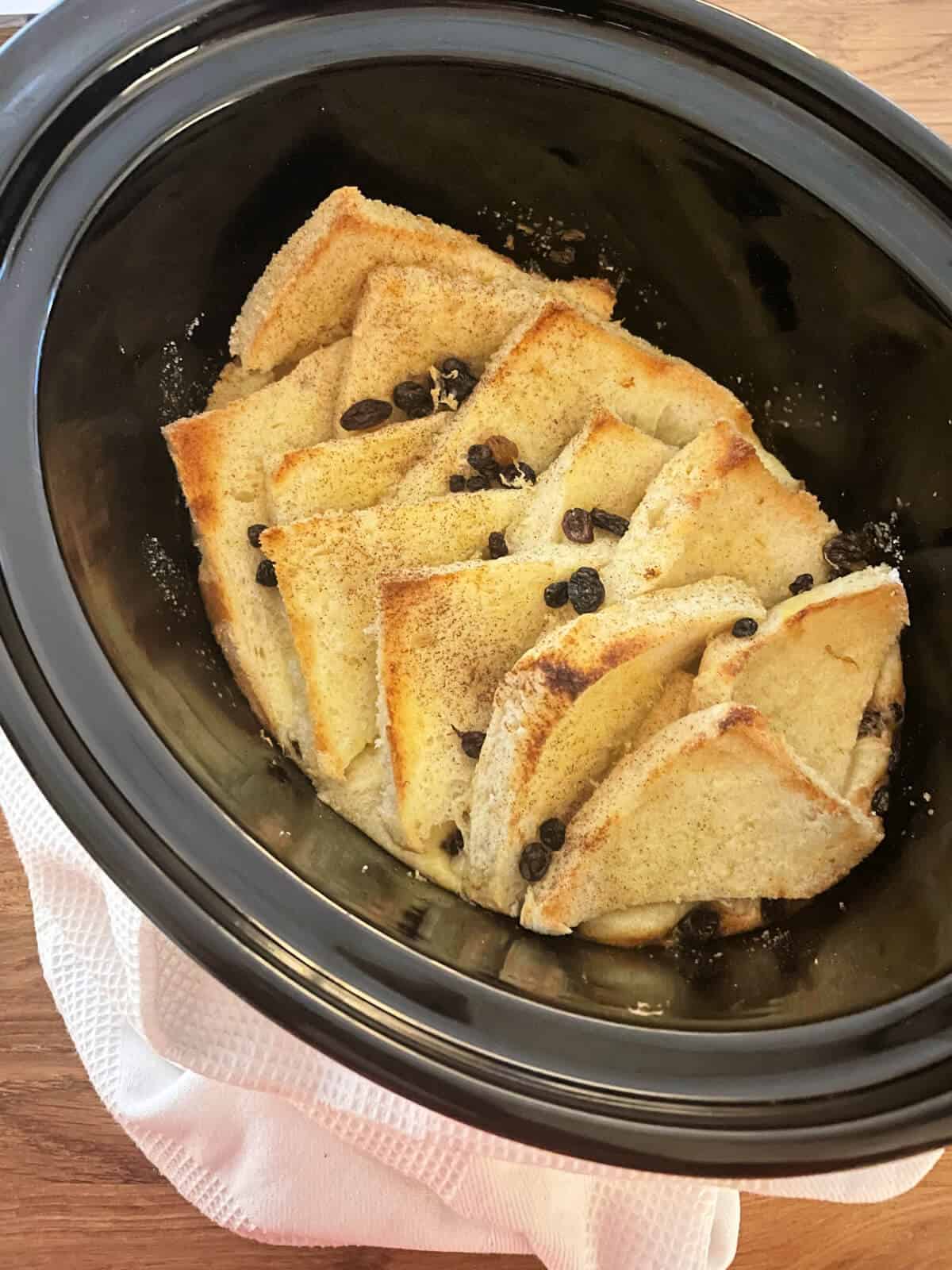 Baked bread and butter pudding in slow cooker pot, ready to serve.