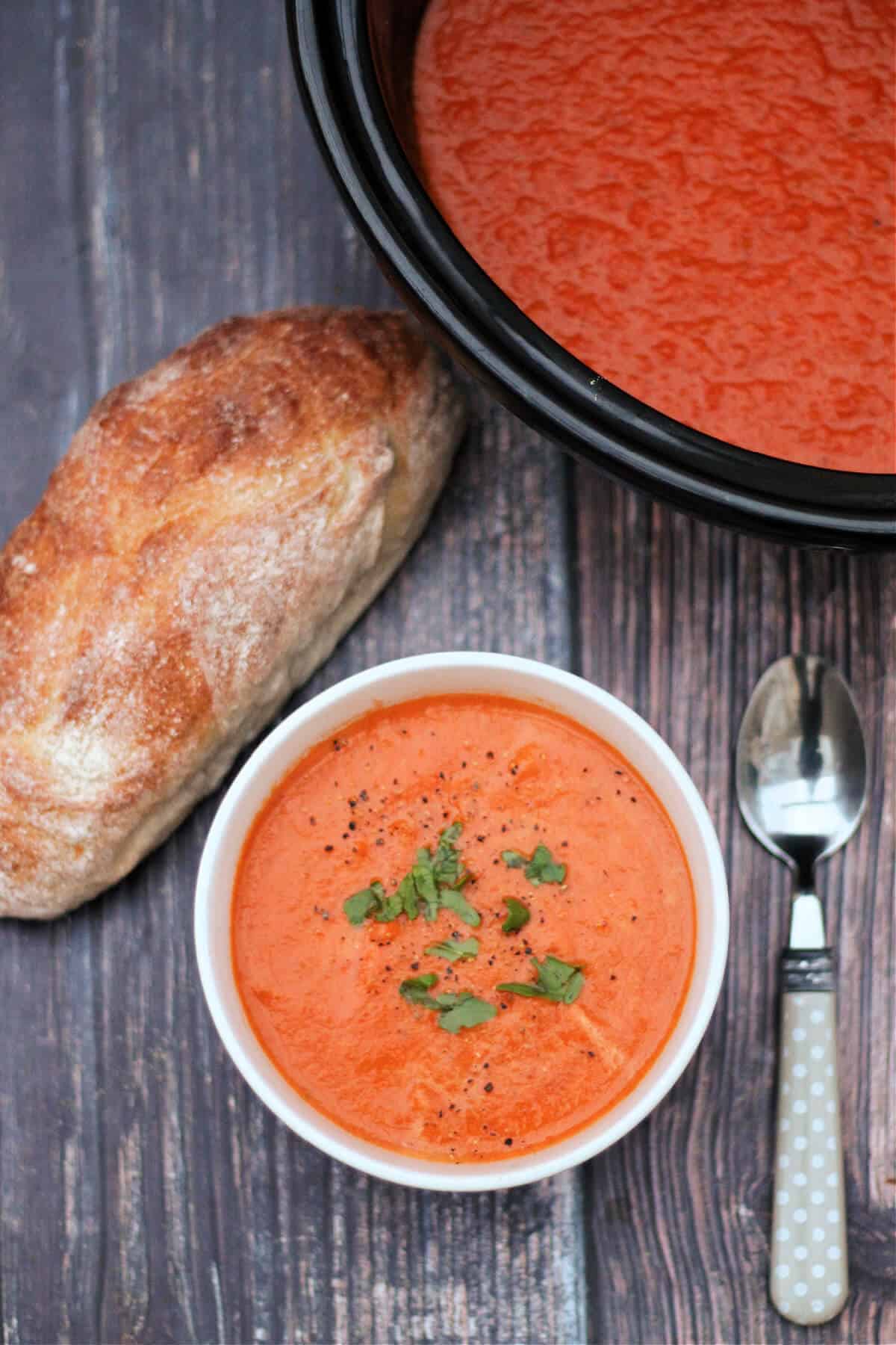 Bowl of soup with bread and serving pot.