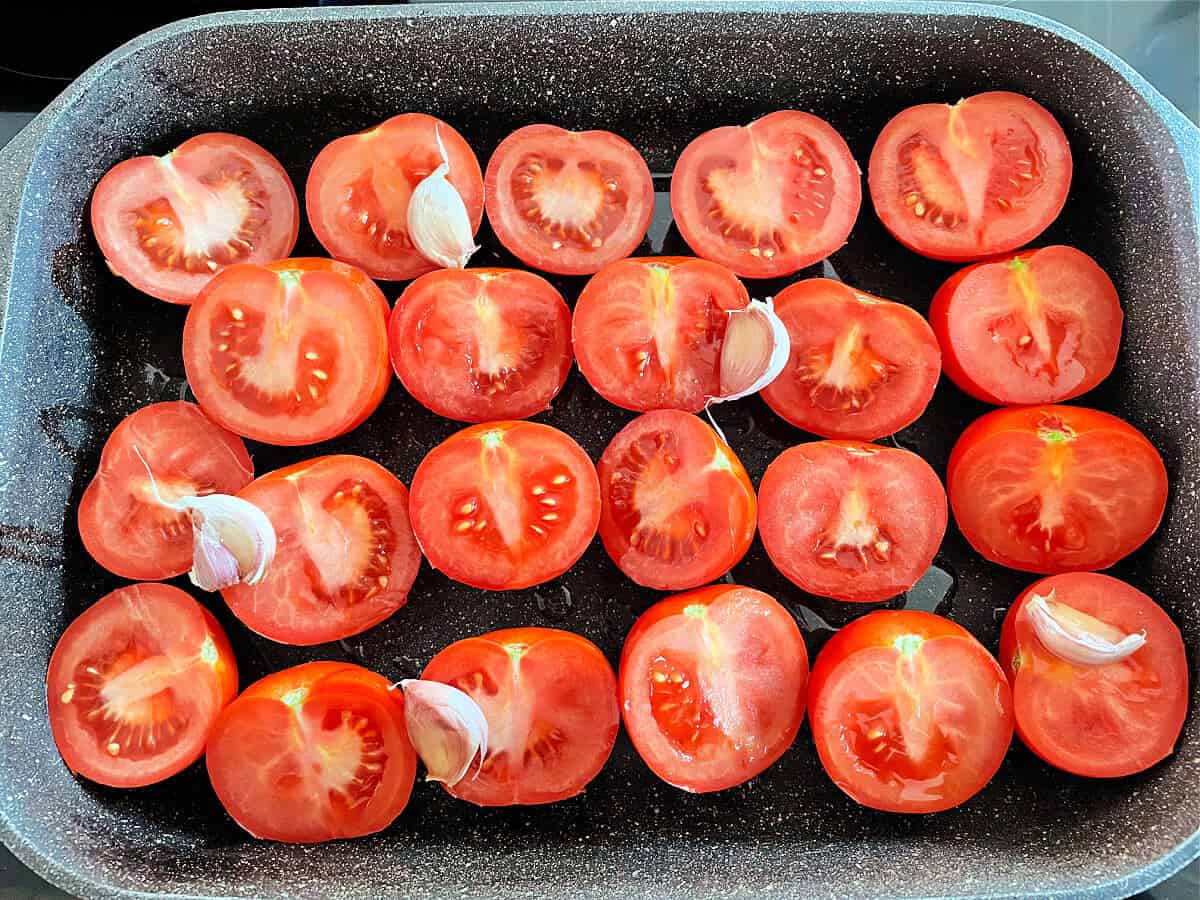 Halved tomatoes in roasting pan.