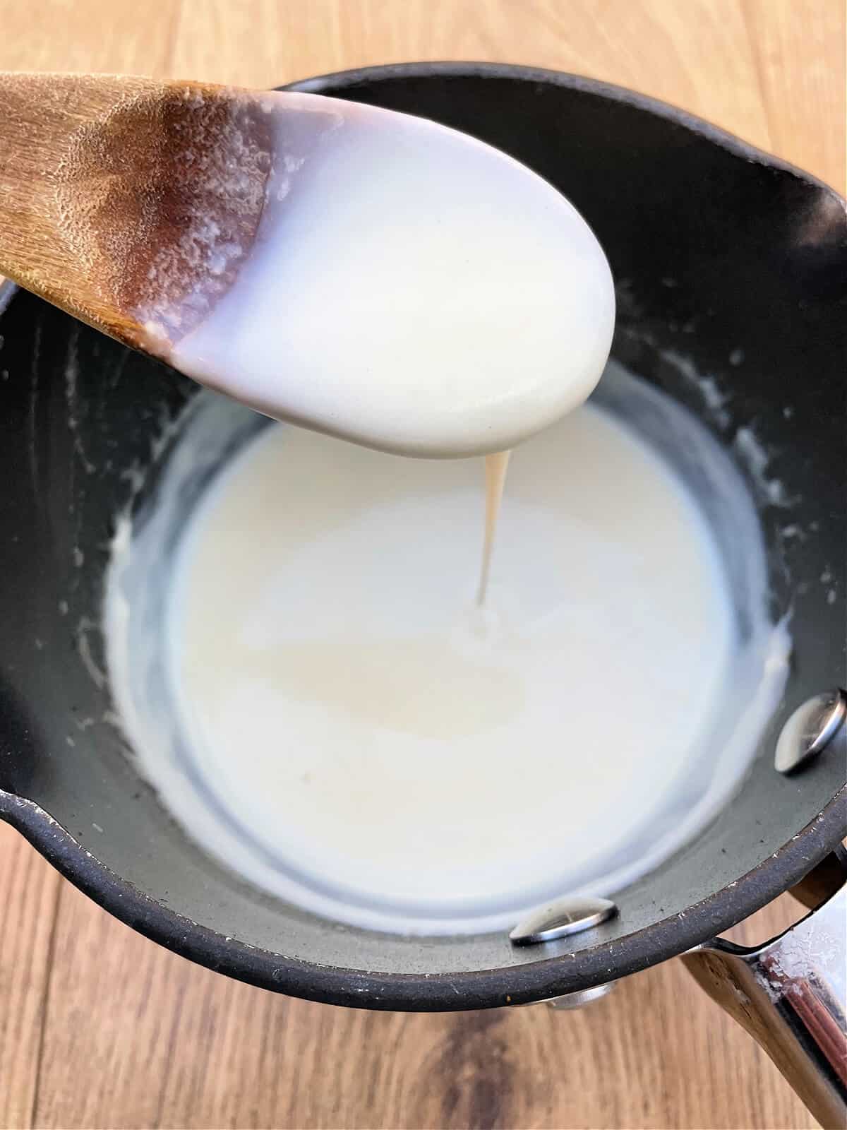 White sauce in a saucepan, with wooden spoon.