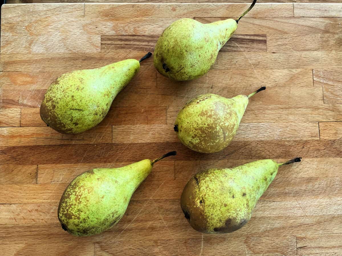 Five pears on a wooden board.