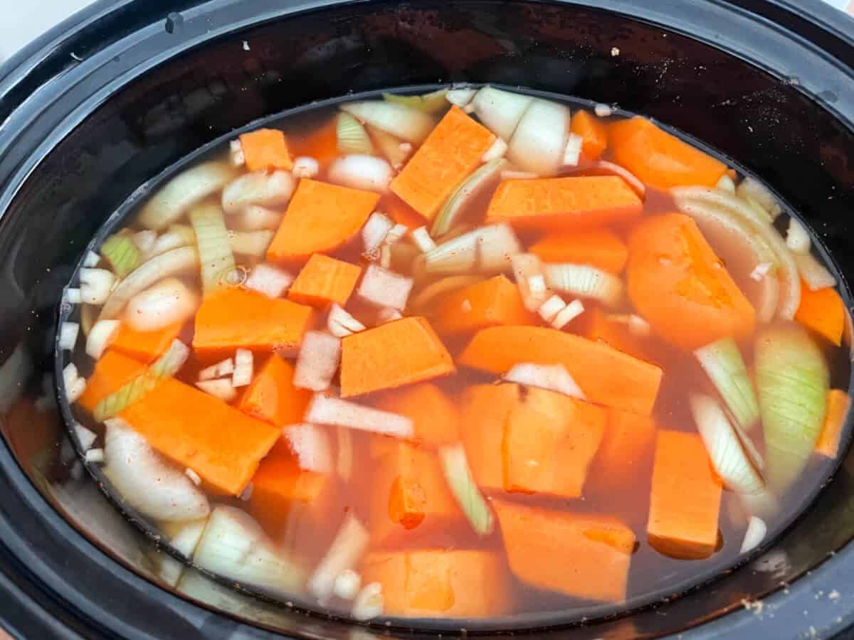 Soup ingredients including vegetable stock in slow cooker ready to cook.