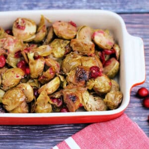 Roasted Brussels sprouts with cranberries in a red serving dish.