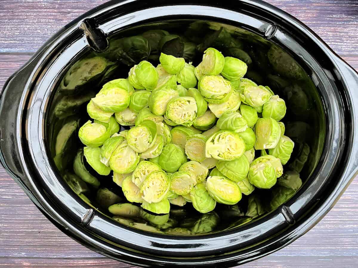 Fresh Brussels sprouts in a slow cooker ceramic pot.
