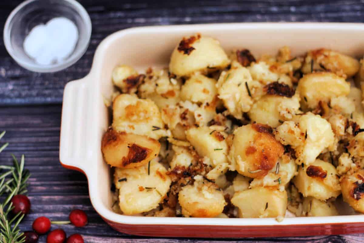 Crunchy slow cooked roast potatoes in red dish.
