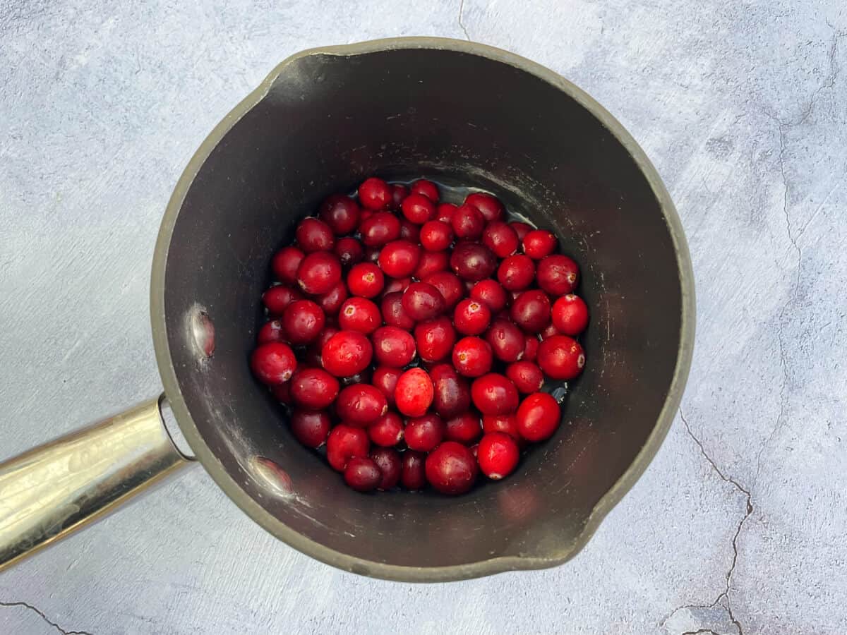 Small saucepan containing cranberries and a little water.