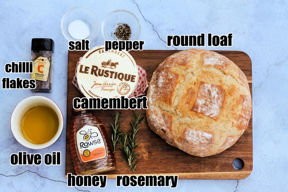 Labelled ingredients for baked camembert on wooden board.