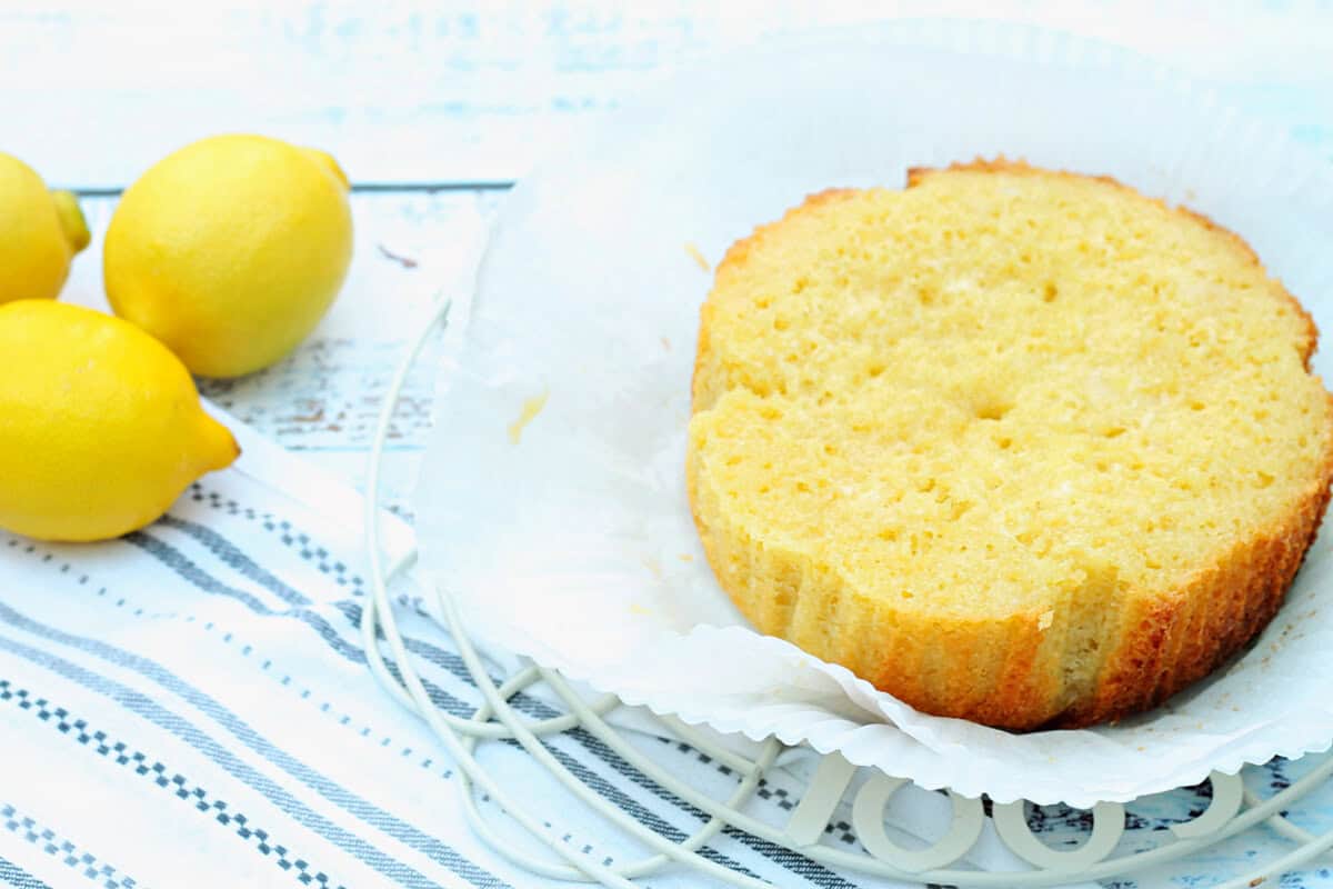 Cake cooling in liner, with lemons to the side.