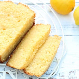 Sliced cake on rack with lemons behind.