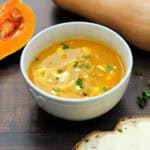 Bowl of soup with swirl of yogurt and garnished with herbs.