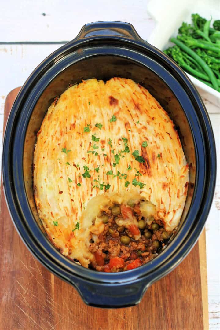 Shepherds pie in slow cooker pot, garnished with herbs.