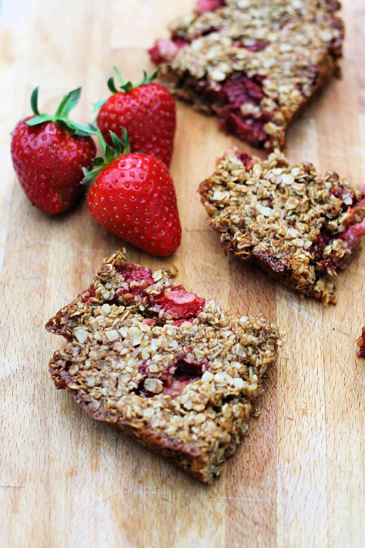 Strawberry oat bars on a wooden chopping board.
