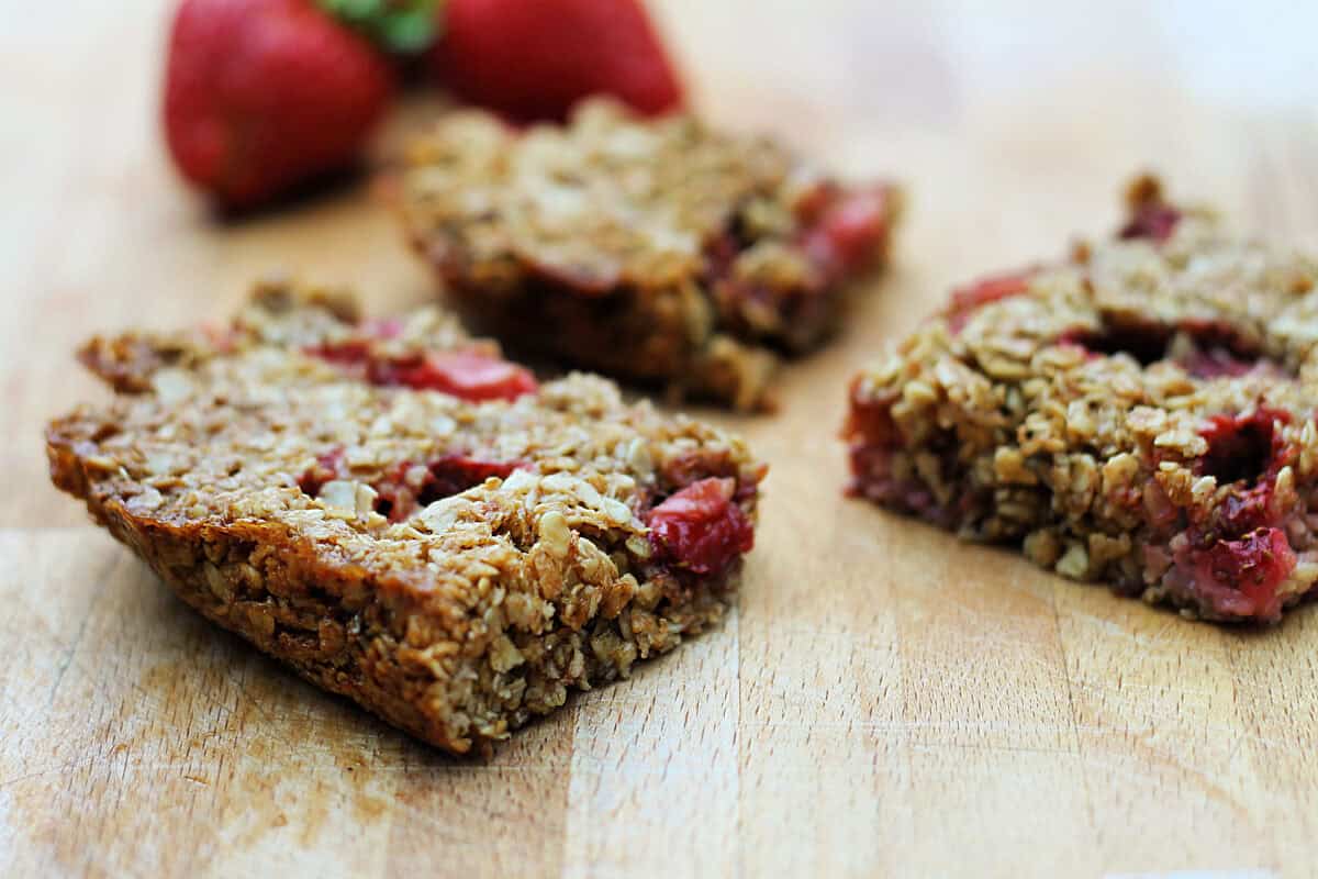 Squares of strawberry flapjacks on a wooden board.