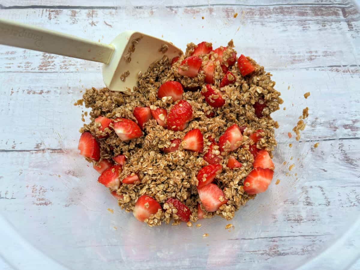 A bowl containing oats and chopped strawberries.