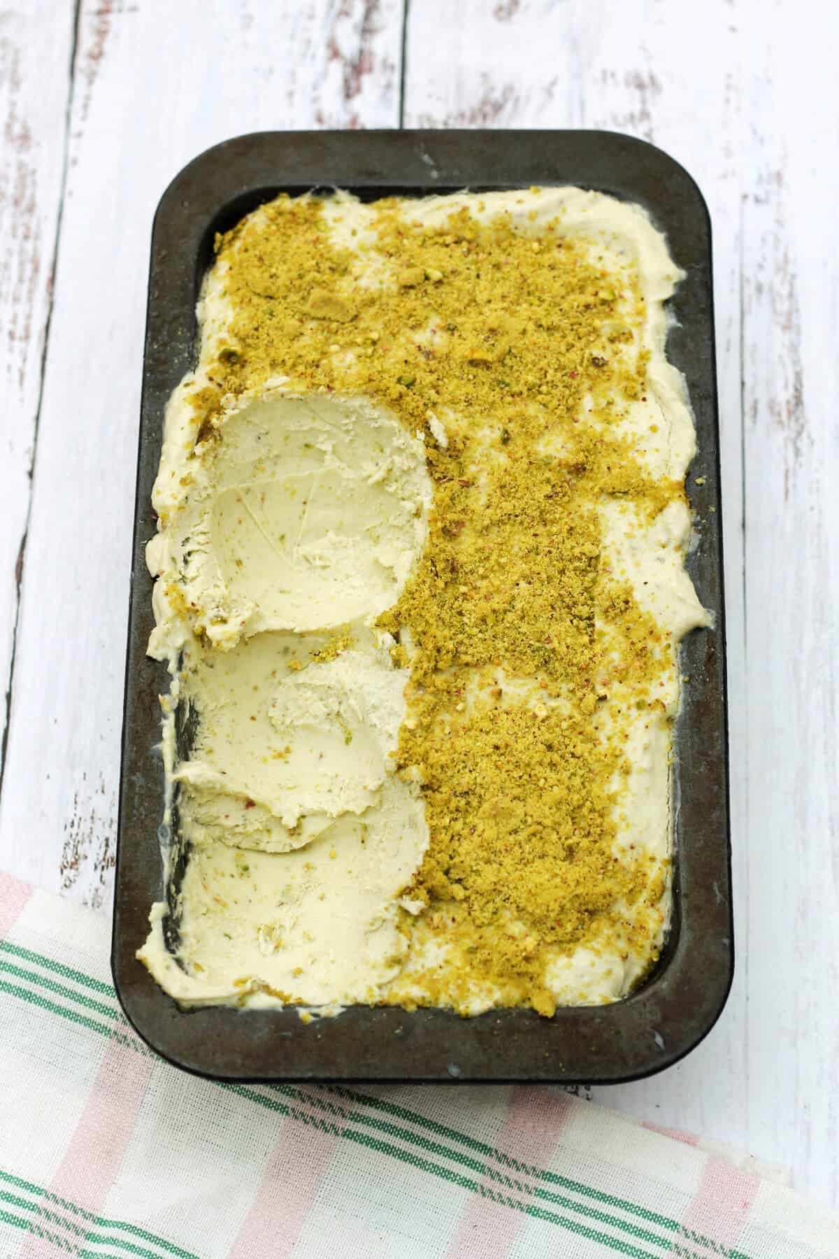 Pistachio ice cream in a loaf tin with some already served.