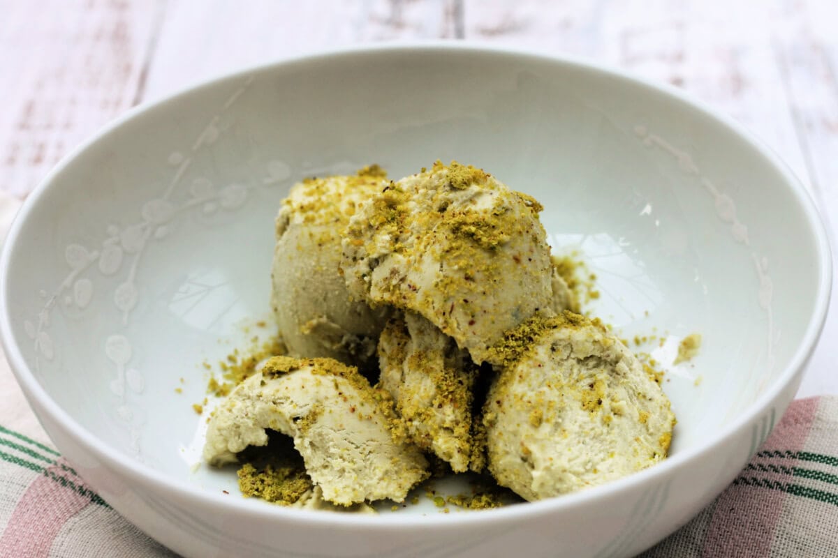 Pistachio ice cream scoops in a white bowl.