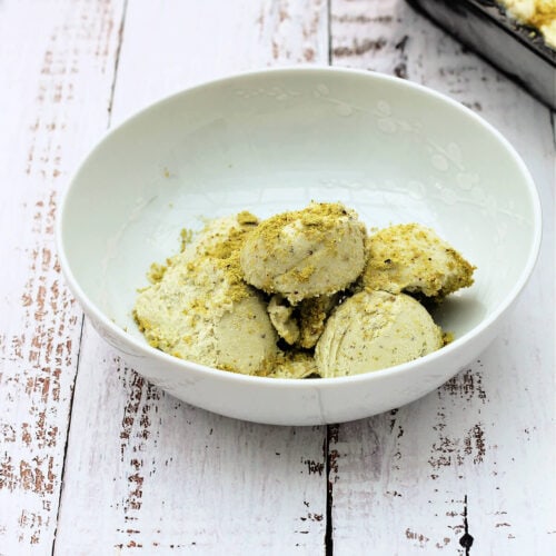 Scoops of pistachio ice cream in a white bowl.