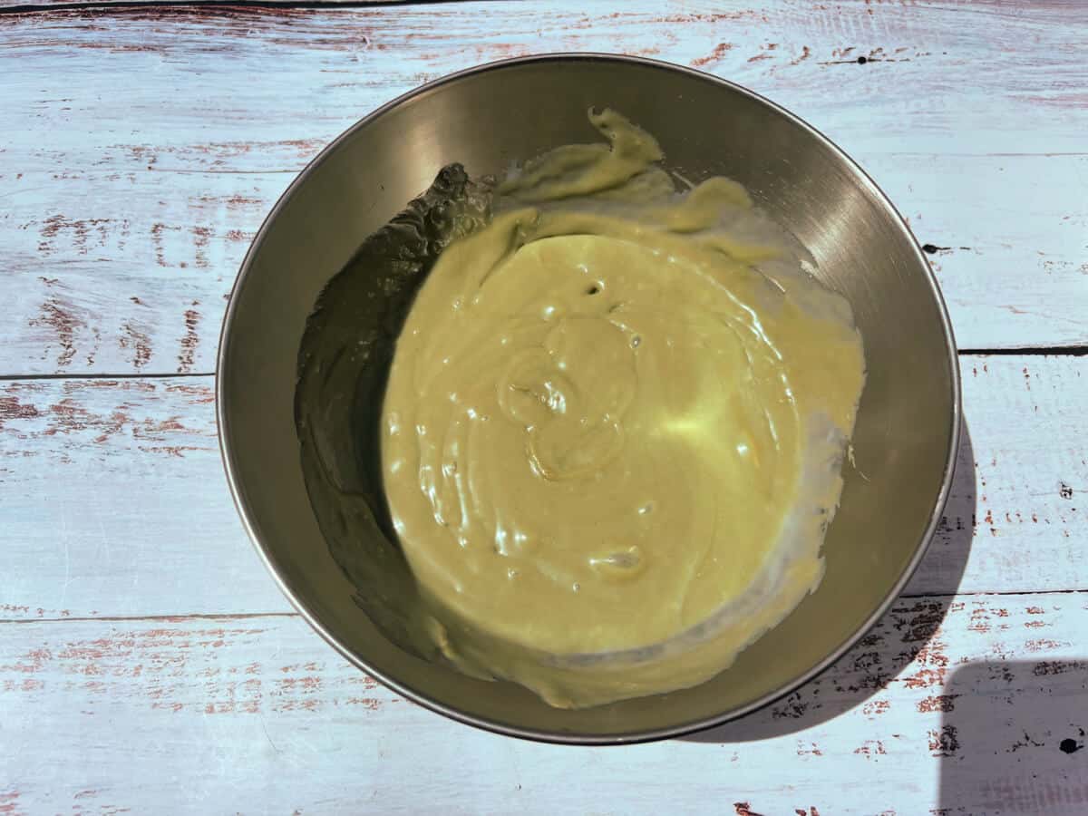 Condensed milk and pistachio cream mixture in a metal bowl.