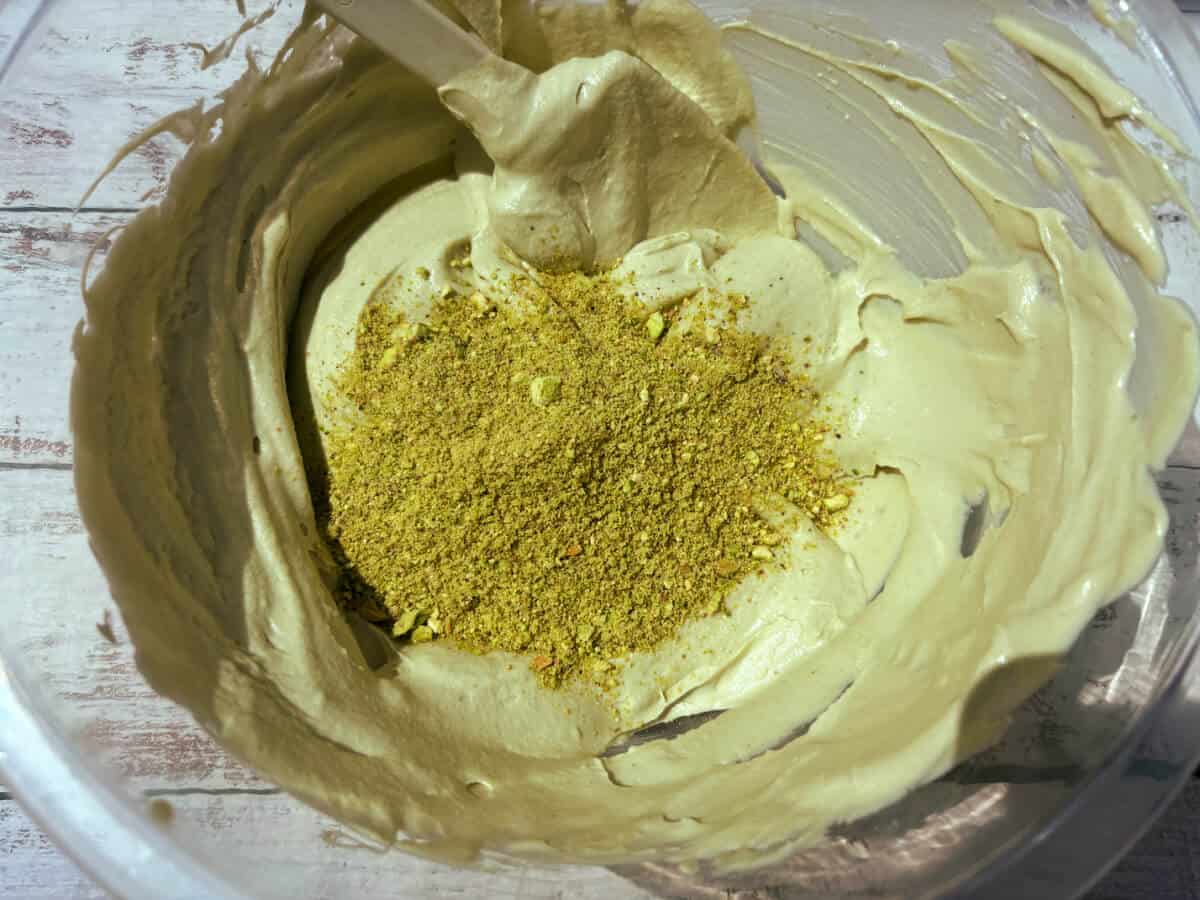 Bowl with ice cream mixture and ground pistachios.