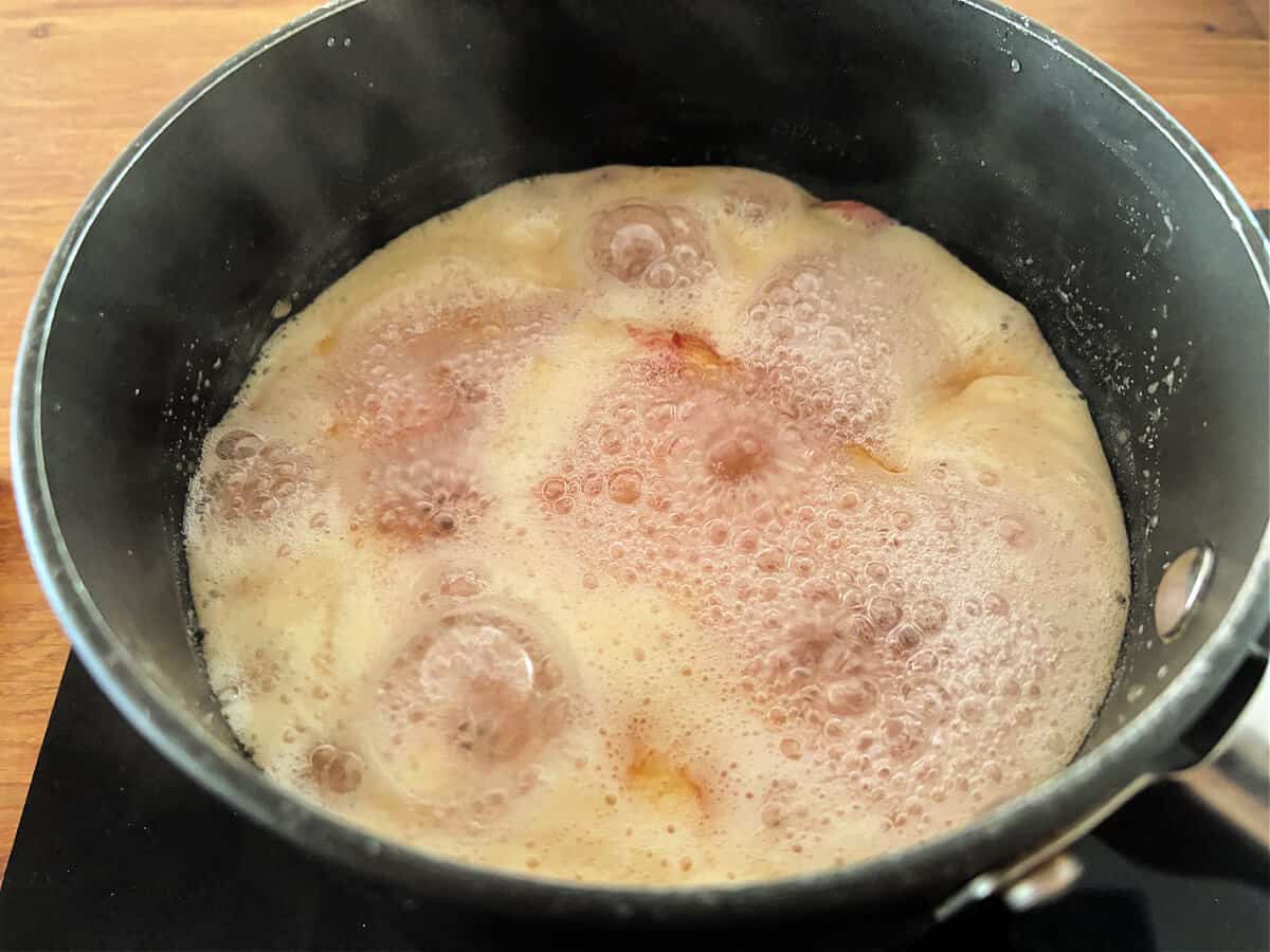 Peach jam boiling in a pan.