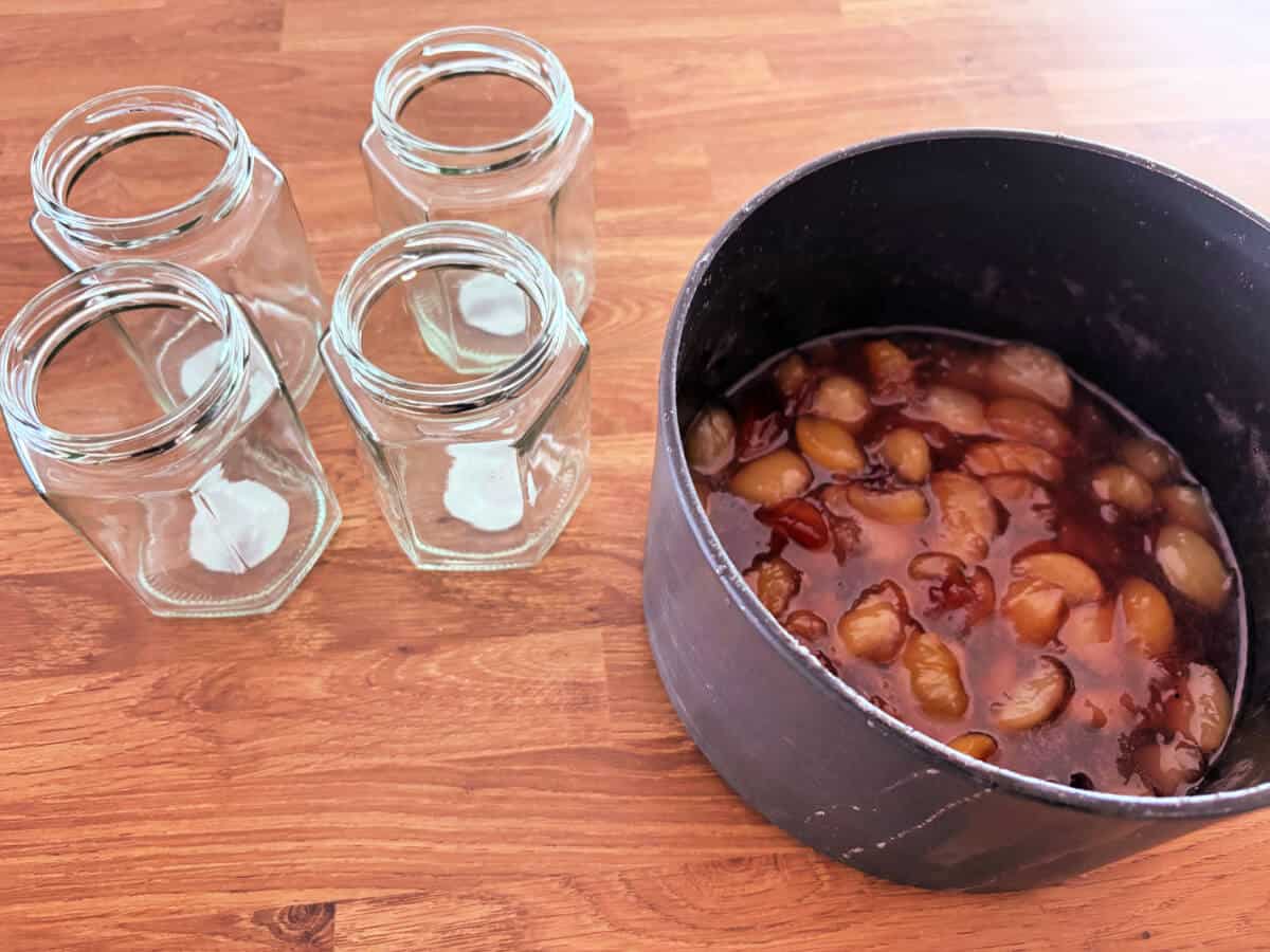 Jam in saucepan with empty jars.